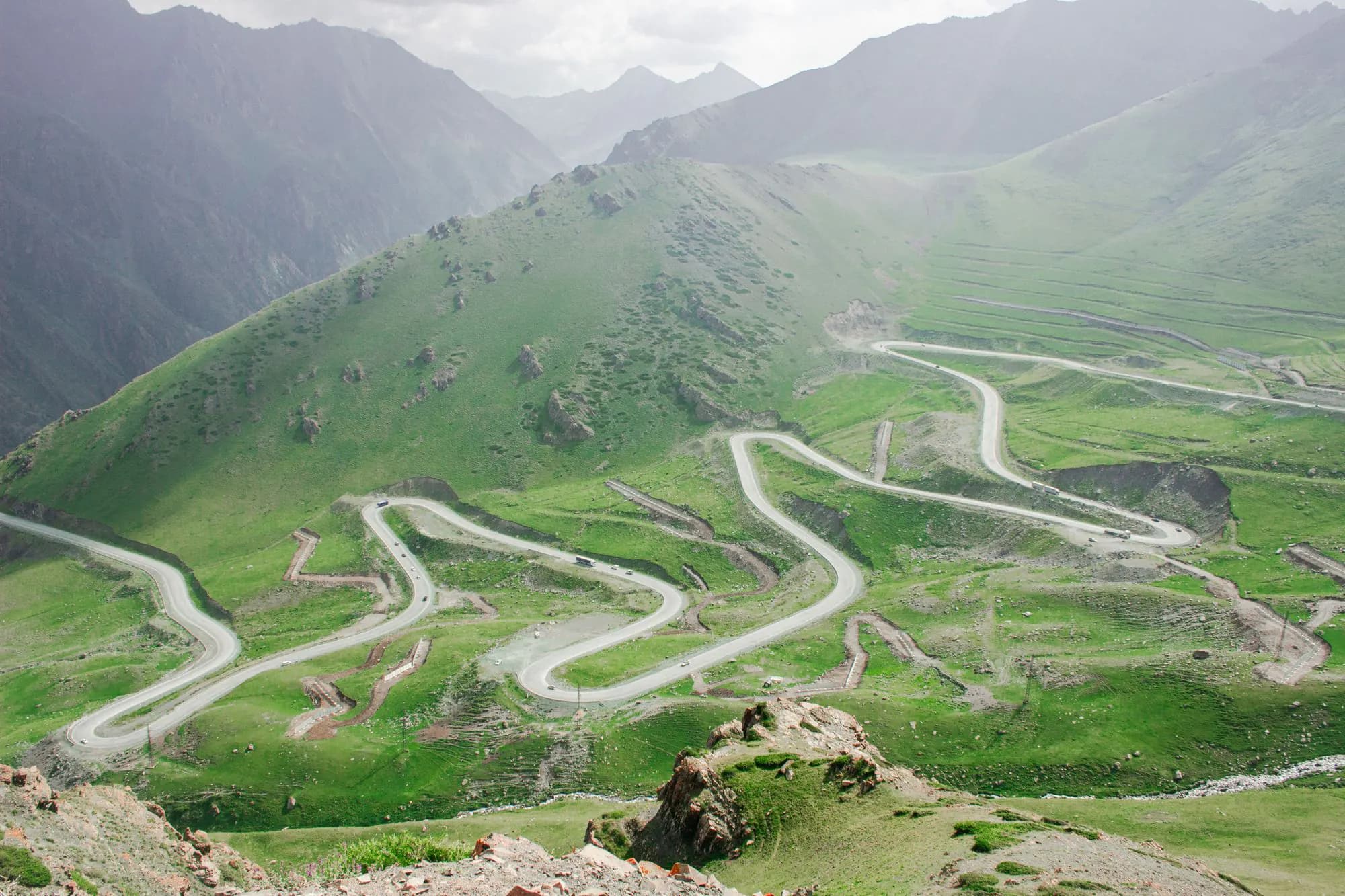 A winding mountain road through green hills in Kyrgyzstan