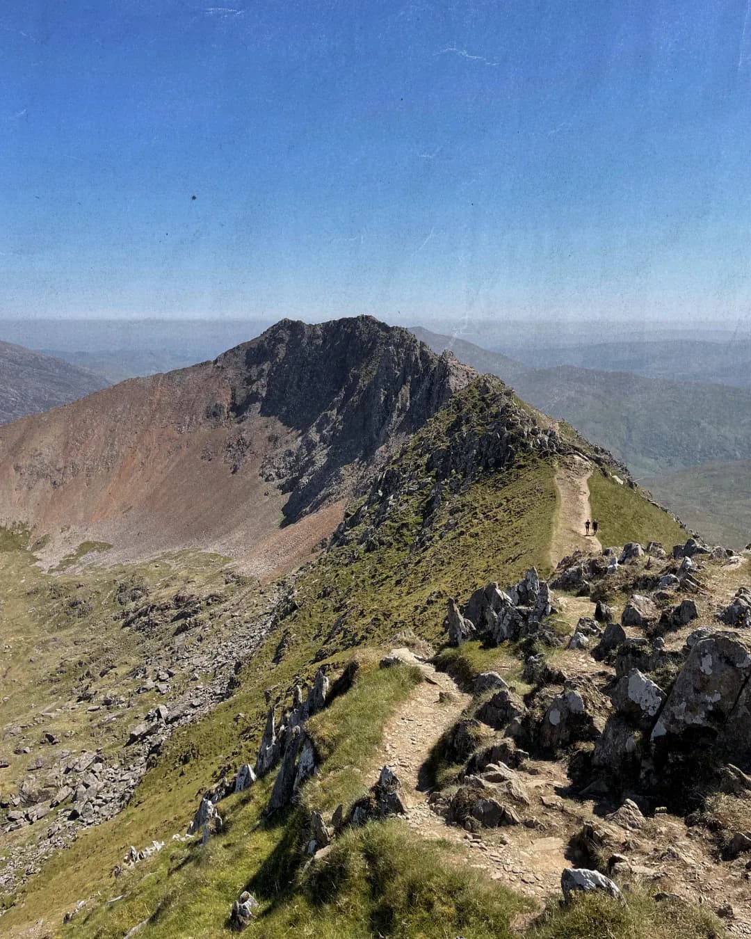 A narrow walking trail along a rugged mountain ridge